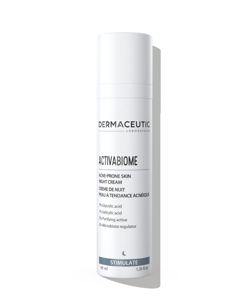 Flaska med Dermaceutic Activabiome nattkräm, en exfolierande och djuprengörande produkt som hjälper till att lösa upp tilltäppteheter, motverka finnar och reducera rodnad. Den arbetar aktivt på förstorade porer och balanserar talgproduktionen med hjälp av salicylsyra, samtidigt som den stödjer hudens naturliga mikrobiom. Flaskans design är enkel med en vit pumpflaska och en etikett som beskriver produktens användning och ingredienser. Nattkräm.